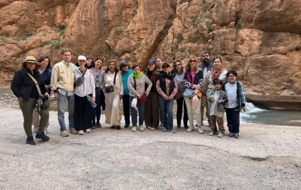 A group of tourists posing between the towering limestone canyon walls of a gorge during a Morocco itinerary 5 days excursion.