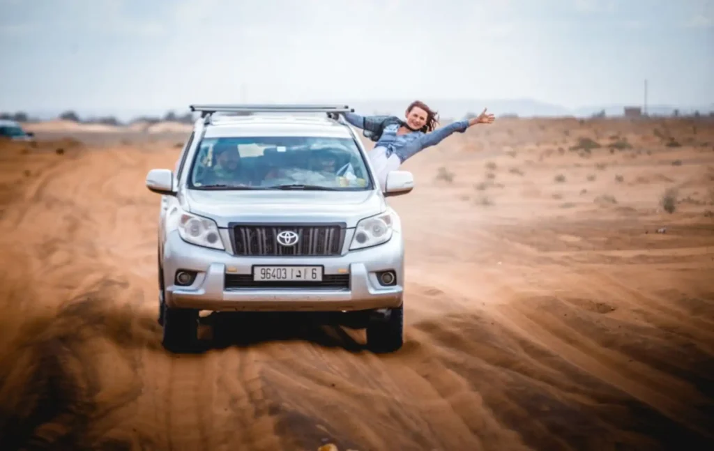 Traveler enjoying Merzouga land cruisers desert excursions in a silver 4x4.