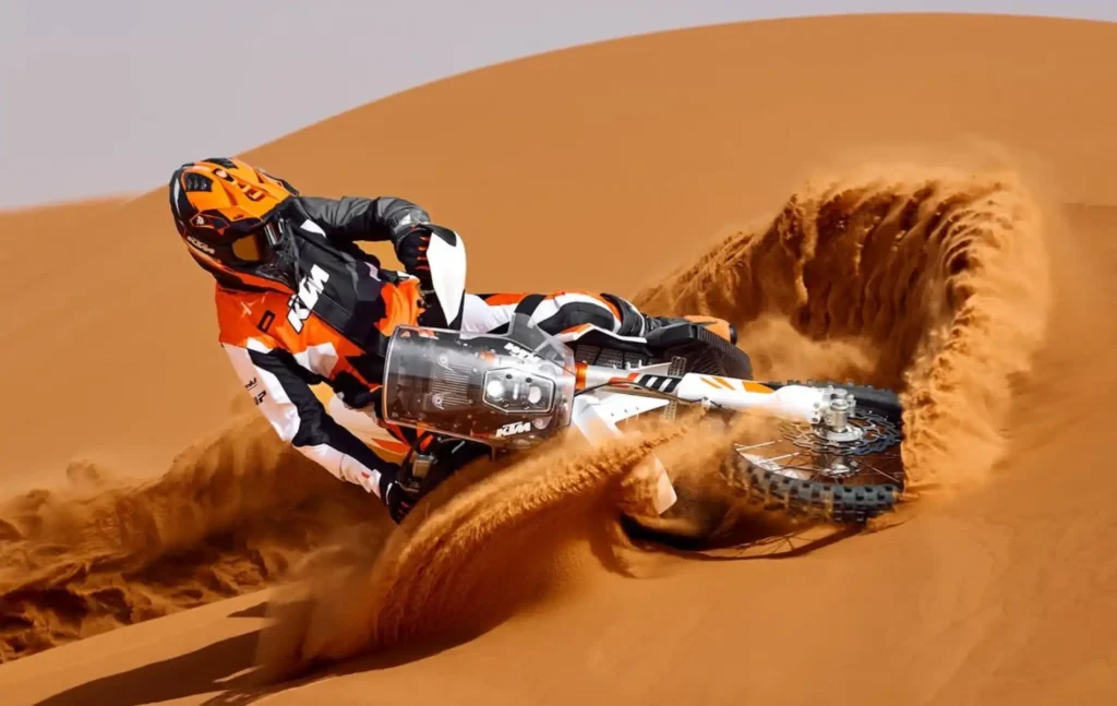 A rider performing a sharp turn and kicking up a wave of sand on a high-performance bike during a ktm merzouga tour.