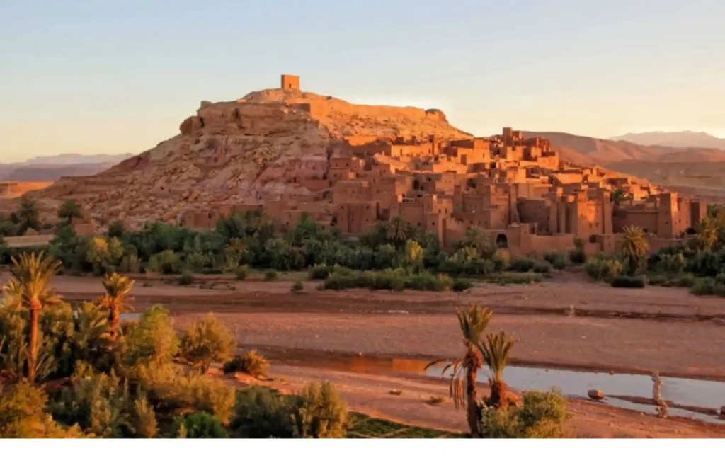 A wide view of the historic Ait Ben Haddou Kasbah at sunset, a highlight of our Marrakech to fes desert tours 4 days.