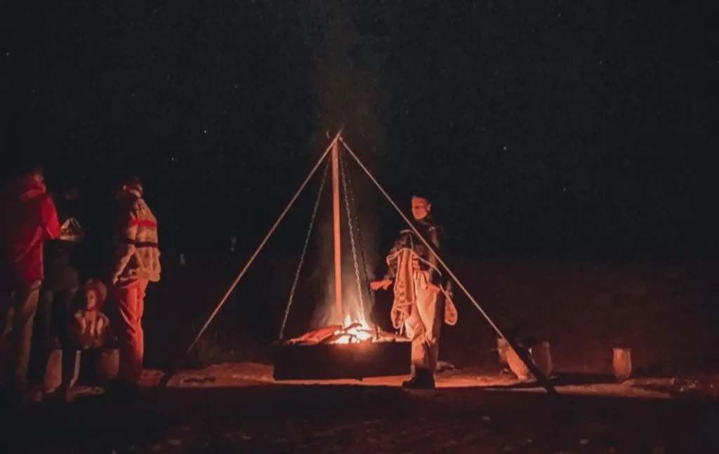 Travelers gathering around a hanging campfire at night during a marrakech to fes desert tour 2 days.