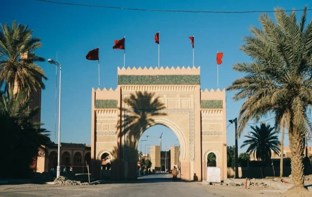 The ornate monumental gate of Rissani with red flags on a 5 days tour from fes to marrakech.
