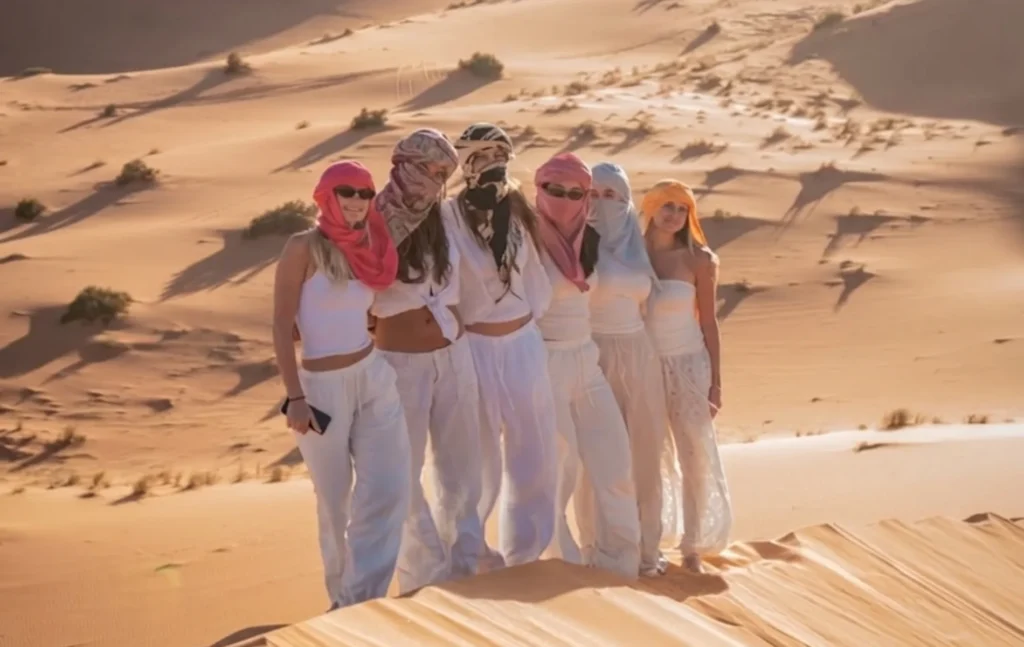 A group of six young women posing in white outfits and colorful turbans during a 5 days Morocco student trip.