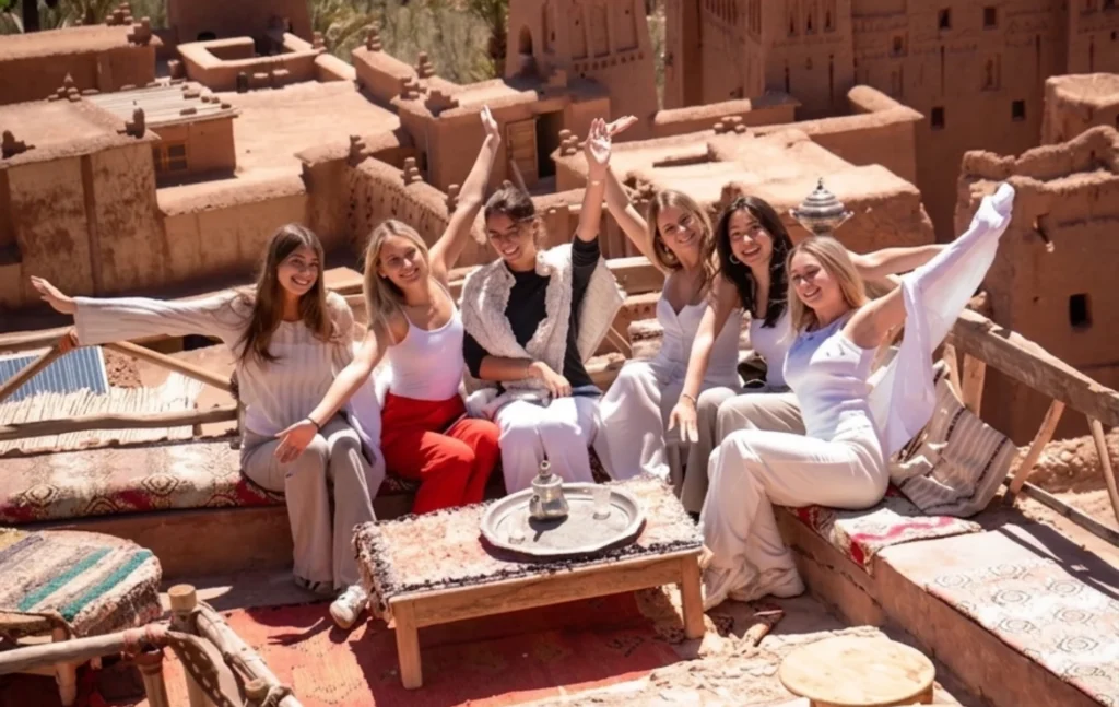 A group of happy friends cheering on a rooftop terrace during a 5 days Morocco student trip.