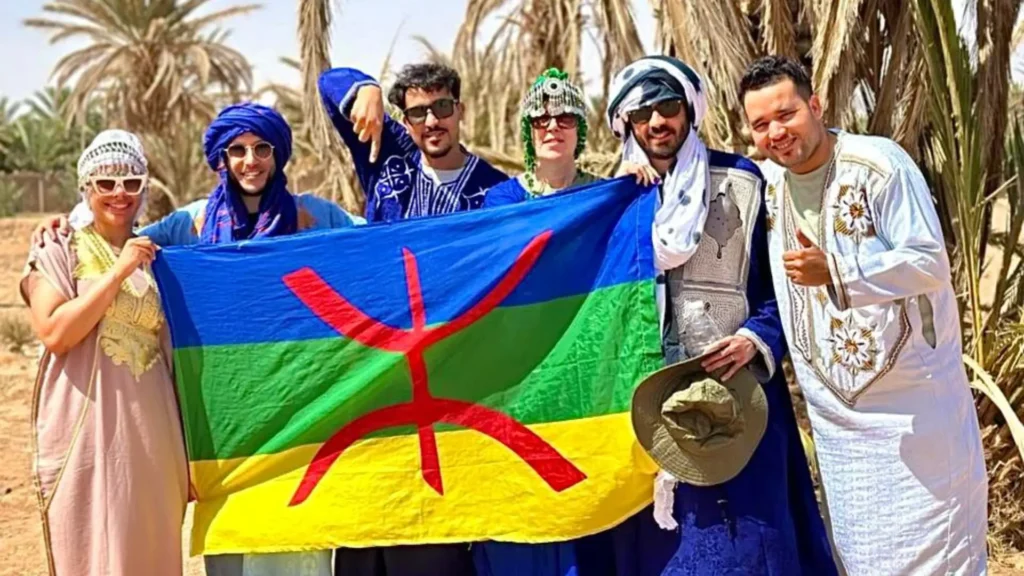 A group of travelers posing with the Berber flag while wearing traditional clothes during Casablanca desert tours, a top highlight for a custom morocco itinerary.