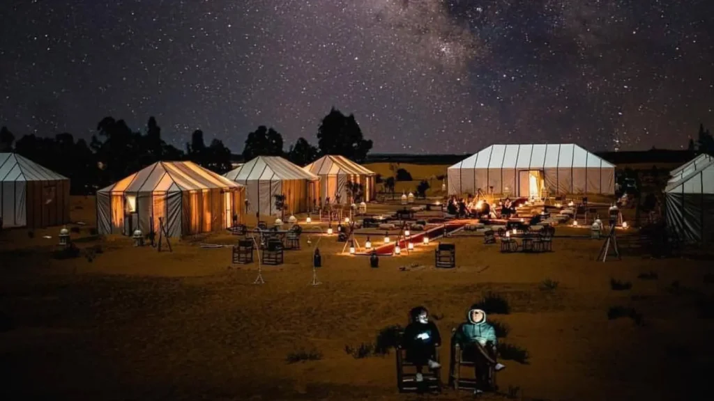 A luxury desert camp illuminated under a starry night sky with the Milky Way visible during Casablanca desert tours, a magical night on a morocco itinerary.