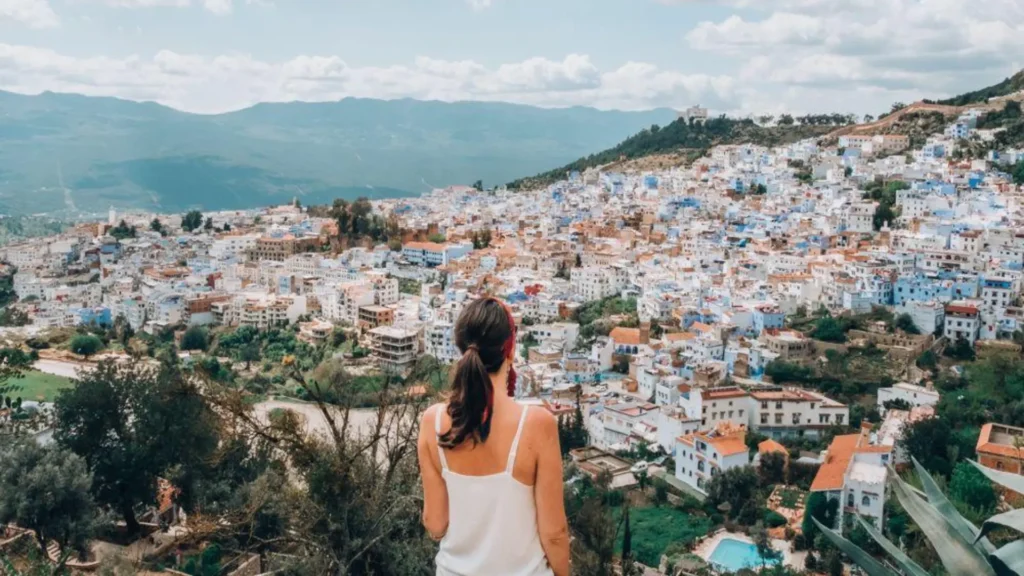 A woman looking over the blue city of Chefchaouen during Casablanca desert tours, a highlight of a custom morocco itinerary.