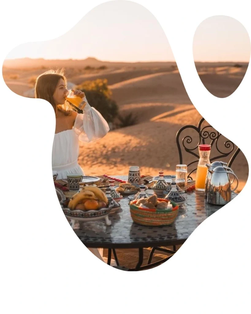 woman enjoying a traditional luxury breakfast in the sand dunes during Casablanca desert tours, a beautiful morning highlight on a morocco itinerary.