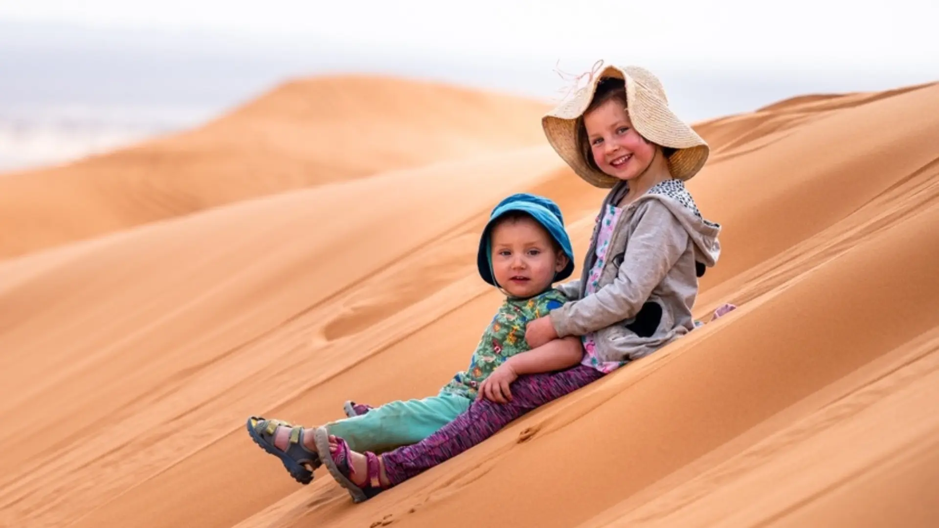 Two children playing on the sand dunes of Merzouga