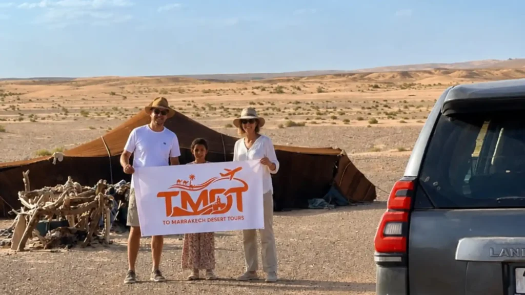 Happy couple and child holding a banner during a desert adventure trip, part of our personalized Morocco Honeymoon Packages and custom getaways.