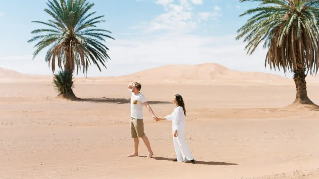 A couple walking hand in hand through the Draa Valley palm grove during our signature Morocco Honeymoon Packages for a romantic oasis escape.