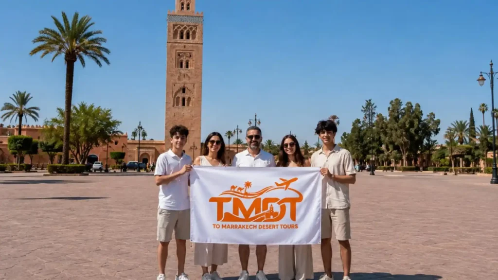 A smiling family holding a tour banner in front of the Koutoubia Mosque in Marrakech during a fun vacation with Morocco Family Tours.