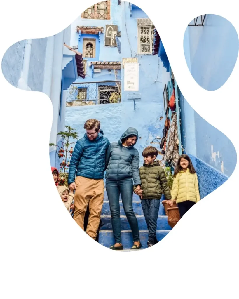 A smiling family walking down the blue-washed steps in the charming streets of Chefchaouen during a vacation with Morocco Family Tours.