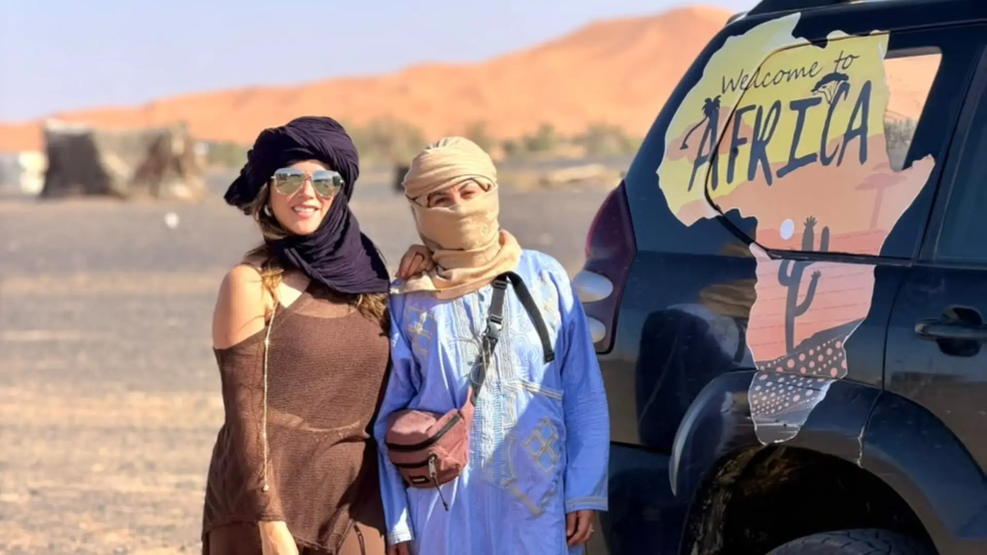Traveler with her guide next to a 4x4 near the Merzouga dunes