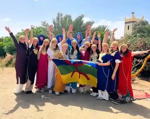 Marrakech student trips: smiling students in traditional Berber clothes holding the Amazigh flag
