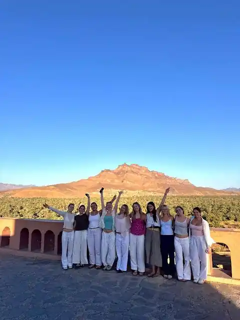 Students tours to Morocco: student group on a terrace above a green palm grove with mountains behind