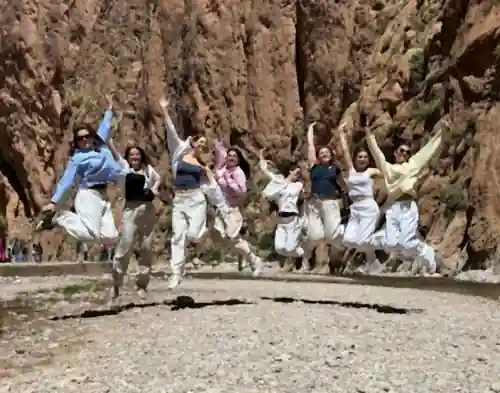 Students tours to Morocco: happy students jumping in the Todgha Gorge between high red cliffs