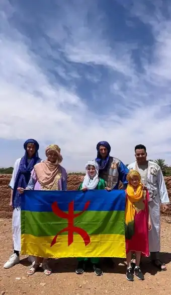 Family of travelers holding the Amazigh flag with their guides