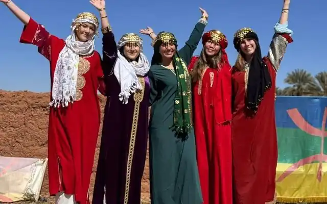 Five travelers wearing traditional Berber dresses during their Sahara desert tour
